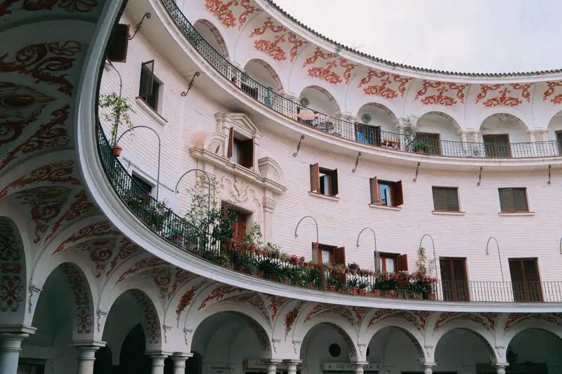 Elegant circular courtyard with ornate arches and balconies in Seville, Spain.