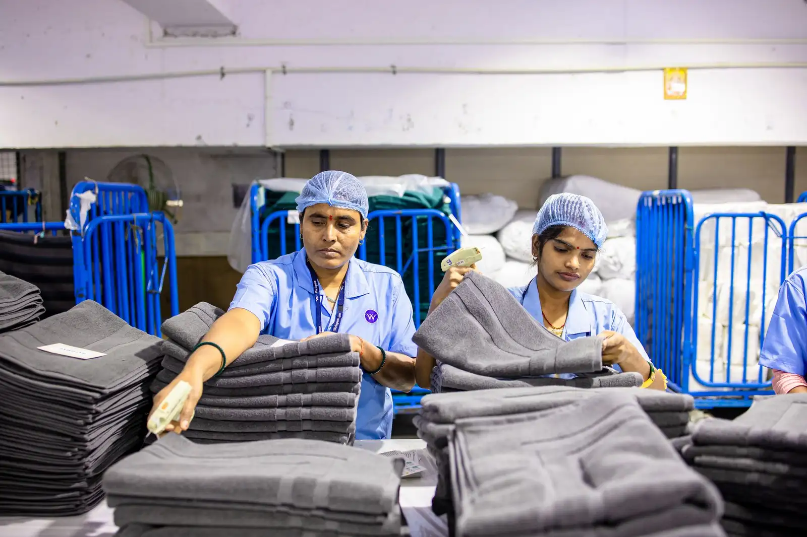 Two Indian factory workers sorting textiles in an indoor facility.