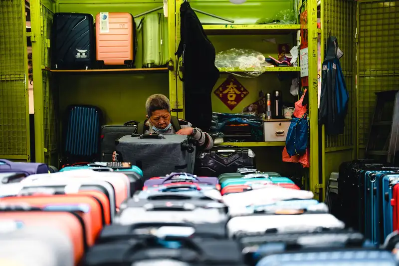 A vendor arranges colorful suitcases in a vibrant market store setting.