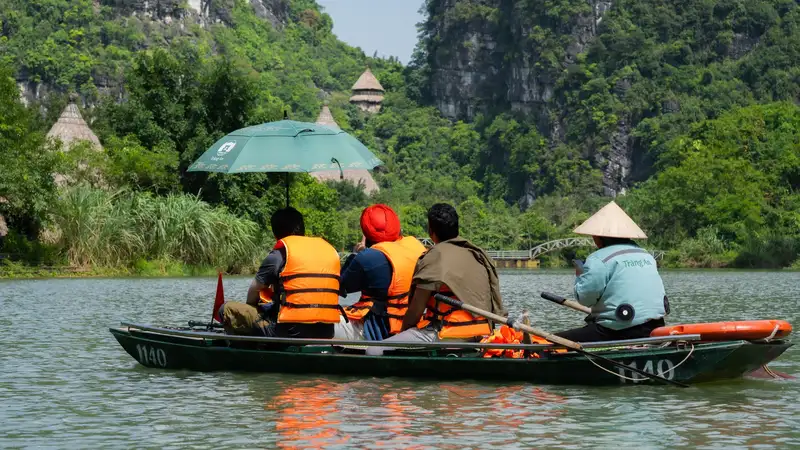 A serene boat ride in Hanoi, Vietnam captured amidst lush greenery and rocky landscapes.