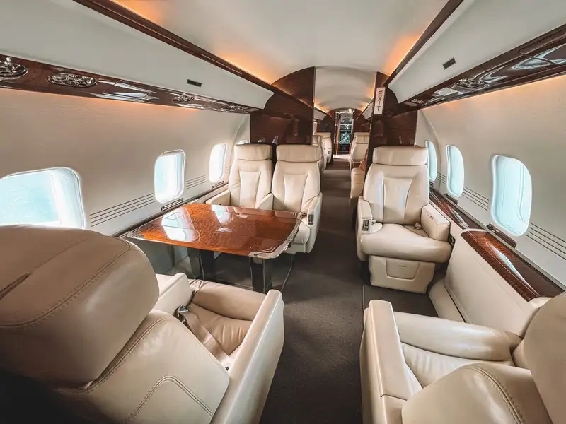 Luxurious interior of a private jet showcasing leather seating and elegant wooden trim.